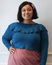 A plus size model wearing a cropped sweater against a white wall