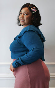 Side pose of a plus size model wearing a cropped sweater with flounce