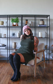 Plus size model in knee-high boots and turtleneck dress leaning back into a chair