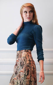 Model looking over shoulder in turtleneck and printed skirt